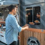 Man receiving orders from a Vendor on a Food Truck