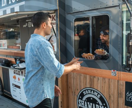 Man receiving orders from a Vendor on a Food Truck