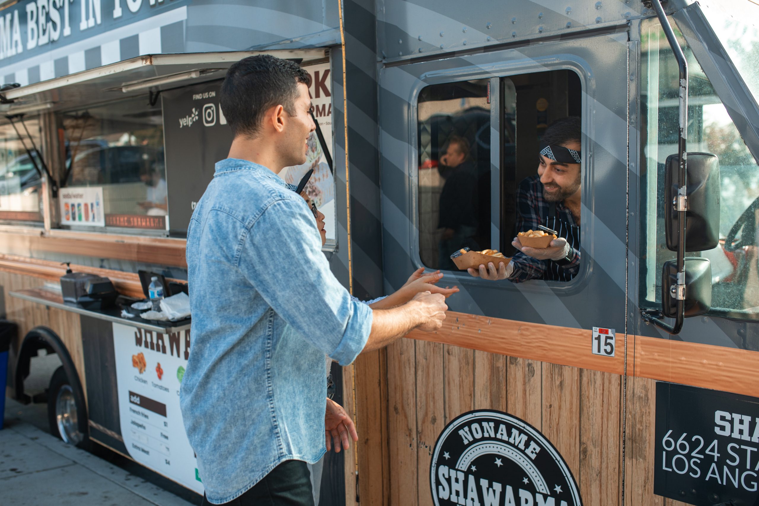 Man receiving orders from a Vendor on a Food Truck